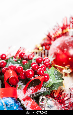 Bordo di Natale con agrifoglio bacche, nastro rosso e ninnolo coperte da neve con copia spazio. Foto Stock