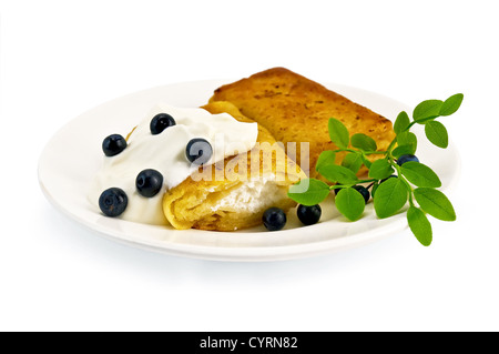 Due frittelle con ricotta, mirtilli e un ramo su un bianco piastra di porcellana, isolato su sfondo bianco Foto Stock