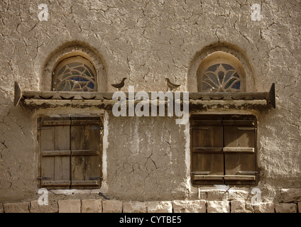 Le finestre di vetro macchiate e uccelli in legno su Shutted Windows, Amran, Yemen Foto Stock