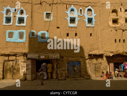 Negozi in un edificio di adobe con dipinto di blu Windows, Amran, Yemen Foto Stock