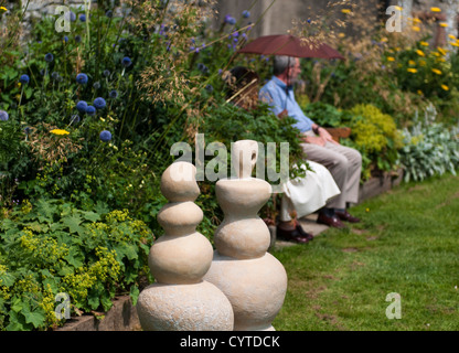 Buckfast, Devon, Inghilterra. Il 26 luglio 2012. Uomo e donna sotto un ombrello rosso per mantenere nell'ombra di un caldo giorno d'estate. Foto Stock