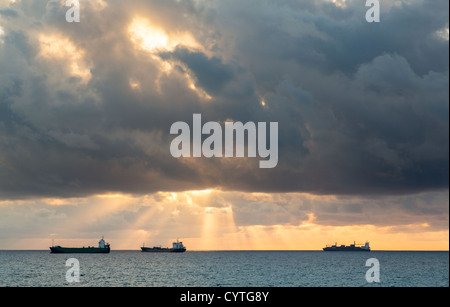 Tre il carico o il nolo di navi per orizzonte al tramonto su nuvoloso burrascosa serata Foto Stock