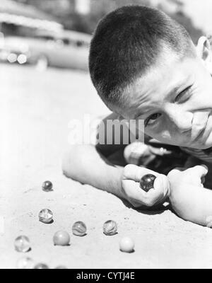 Close-up del giovane ragazzo giocando marmi nello sporco Foto Stock