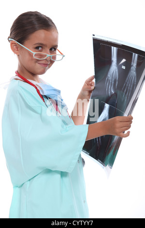 Bambina indossa hospital scrubs e l'esame di una xray Foto Stock