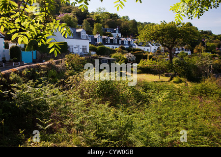 Vista di una fila di case che si affacciano su giardini nel villaggio costiero di Corrie, Isle of Arran, Scotland, Regno Unito Foto Stock