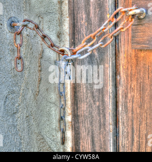 Il lucchetto della catena su una porta di legno Foto Stock