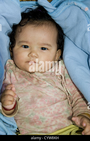 A quattro mesi di vecchia bambina giace in un cestello (non visibile), Dhoban villaggio lungo il sentiero di Manaslu, Nepal Foto Stock