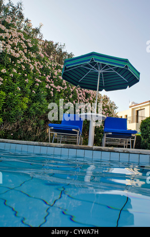 Sedie e ombrellone vicino alla piscina Foto Stock