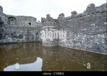 BEAUMARIS, Galles: L'imponente fossato e la porta fortificata del castello di Beaumaris sono una testimonianza dell'ingegneria militare medievale sull'isola di Anglesey. Commissionato da re Edoardo i alla fine del XIII secolo come parte della sua campagna per sottomettere il Galles, questo capolavoro incompiuto rappresenta l'apice del design concentrico del castello. Il suo layout simmetrico e l'elaborato sistema di difesa, incluso il fossato pieno d'acqua, dimostrano la brillantezza strategica del Maestro Giacomo di San Giorgio, maestro costruttore di Edoardo. Foto Stock