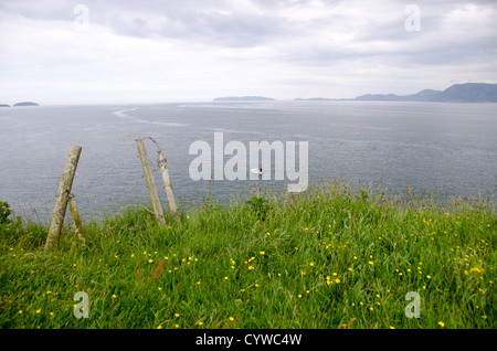 BEAUMARIS, Galles — le acque dello stretto di Menai si estendono da Beaumaris sull'isola di Anglesey. Questo stretto canale di marea separa Anglesey dal Galles continentale, con le montagne di Snowdonia visibili all'orizzonte. Lo stretto collega il Mare d'Irlanda alla Baia di Caernarfon ed è noto per le sue forti correnti di marea. Beaumaris, situata sulla costa sud-orientale di Anglesey, si trova lungo questa via d'acqua che è stata un'importante rotta marittima per secoli. La città è posizionata in vista della terraferma gallese attraverso lo stretto. Foto Stock