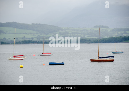 BEAUMARIS, Anglesey, Galles - barche a vela in legno ormeggiate sulle acque calme dello stretto di Menai vicino a Beaumaris, sull'isola di Anglesey nel Galles settentrionale. La barca è ormeggiata vicino al porto della città, con vedute panoramiche dello stretto e della costa circostante, un luogo popolare per la vela e le attività marittime. Foto Stock