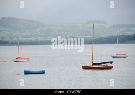 BEAUMARIS, Anglesey, Galles - barche a vela in legno ormeggiate sulle acque calme dello stretto di Menai vicino a Beaumaris, sull'isola di Anglesey nel Galles settentrionale. La barca è ormeggiata vicino al porto della città, con vedute panoramiche dello stretto e della costa circostante, un luogo popolare per la vela e le attività marittime. Foto Stock