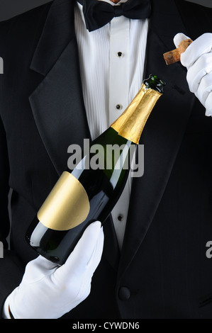 Primo piano di un sommelier stappare una bottiglia di champagne. L uomo è irriconoscibile indossando uno smoking e guanti bianchi. Formato verticale. Foto Stock