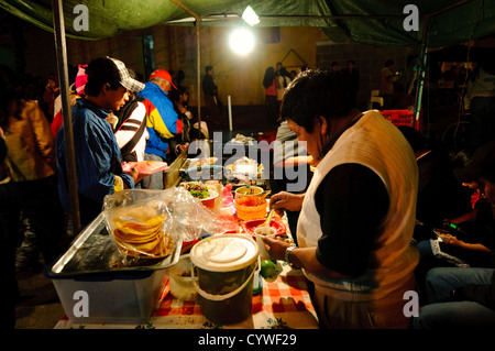 Cena in un cibo di strada vendor come parte di un mercato notturno impostata per la festa di Nostra Signora di Guadalupe giorno in Antigua, Guatemala. Foto Stock