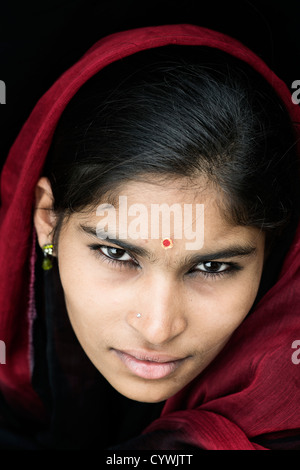 Ragazza indiana indossando un velo di colore rosso su sfondo nero. Andhra Pradesh, India Foto Stock