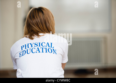 Ragazza facendo educazione fisica in palestra di una scuola secondaria, Wales UK Foto Stock