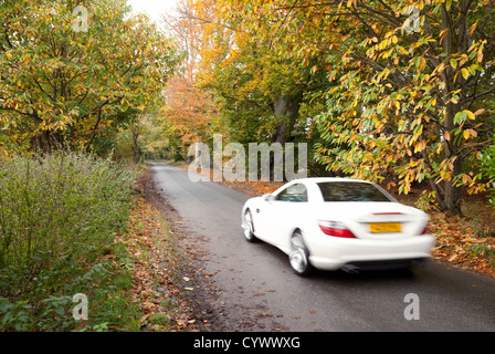 Un bianco auto sportiva accelerando su una stretta strada di campagna, Suffolk East Anglia UK Foto Stock
