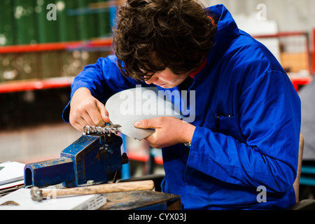 Un ragazzo adolescente il taglio di metallo pratico apprendimento competenze meccaniche in un secondario completo scuola workshop in Galles REGNO UNITO Foto Stock