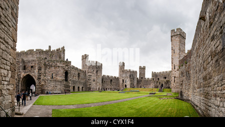 CAERNARFON, Galles: Il cortile interno del castello di Caernarfon mostra le caratteristiche torri poligonali e le mura difensive della fortezza medievale. Costruito da Edoardo i durante la sua conquista del Galles alla fine del XIII secolo, il castello servì come simbolo del dominio inglese e in seguito divenne il sito tradizionale per l'investitura del principe di Galles. Il sito patrimonio dell'umanità dell'UNESCO fa parte dell'anello di ferro di Edoardo i nel Galles del Nord. Il design unico del castello di Caernarfon è stato ispirato dalle mura di Costantinopoli, con muratura a fasce e torri angolari piuttosto che dal tipico cerchio Foto Stock