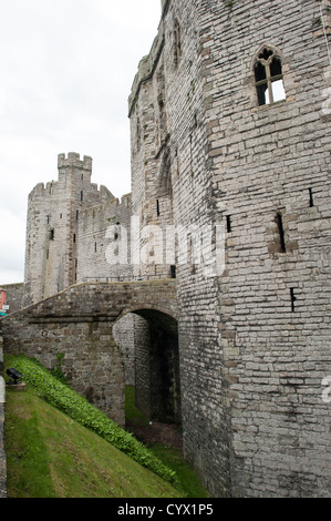 Caernarfon Castle Main Gatehouse Caernarfon Wales / CAERNARFON, Galles - la porta del Re, la porta principale del castello di Caernarfon, sorge sopra l'ingresso della fortezza medievale nel Galles nord-occidentale. Un normanno motte-and-bailey si trovava su questo sito dalla fine dell'XI secolo, ma re Edoardo i commissionò l'imponente struttura vista oggi nell'estate del 1283 come parte della sua conquista del Galles, con la costruzione sotto il maestro Giacomo di San Giorgio che continuò fino al 1330 circa. La porta d'ingresso fissa una fortezza rinomata per le sue caratteristiche torri poligonali e le imponenti mura di cinta, caratteristiche che la collocano Foto Stock