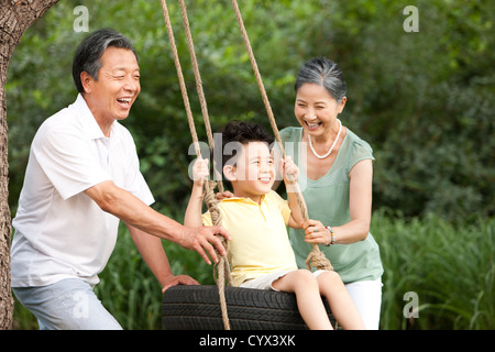 Nonni e nipote giocando su uno swing Foto Stock