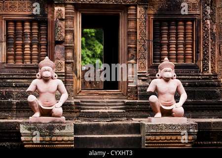 Statue guardia dell'ingresso per un intricatamente scolpito Banteay Srei tempio di Angkor Wat un sito patrimonio mondiale dell'unesco in Cambogia Foto Stock