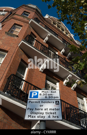 I titolari di autorizzazioni e pagare nei parcheggi a firmare in Hammersmith, Londra, Inghilterra, con blocco di dimora in background Foto Stock