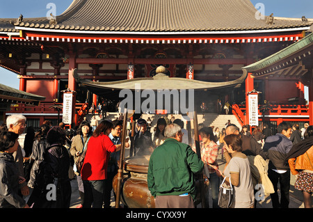 Una folla di persone intorno al bruciatore di incenso presso la sala principale del Tempio di Senso-ji ad Asakusa, Tokyo, Giappone Foto Stock