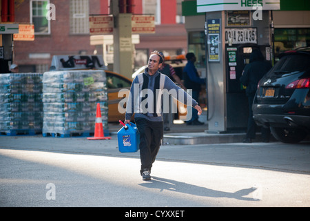 Linea di persone fino ad acquistare benzina a un Hess stazione di gas nel quartiere di Clinton di Manhattan a New York Foto Stock