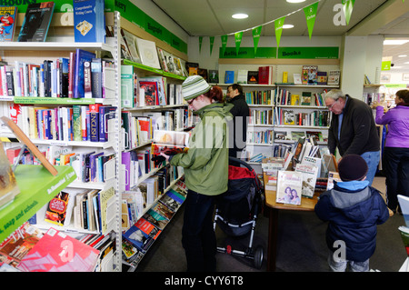 Persone libri di esplorazione in una carità Oxfam shop in Inghilterra Foto Stock