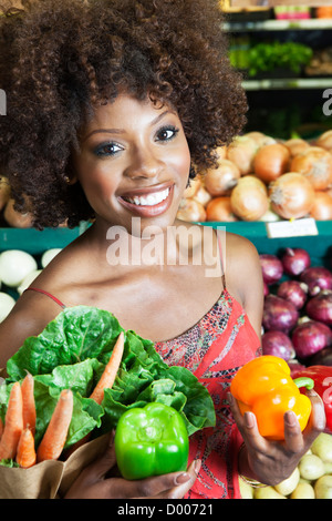 African American donna tenendo i peperoni e verdure al supermercato Foto Stock