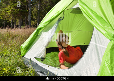 Bella ragazza in un abito rosso in una tenda in una foresta Foto Stock