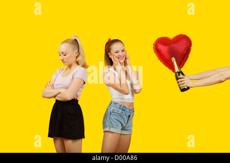 Mano d'uomo gifting a forma di cuore ad palloncino e bottiglia di champagne a sorpresa la donna con un amico sensazione lasciata fuori in piedi dietro Foto Stock