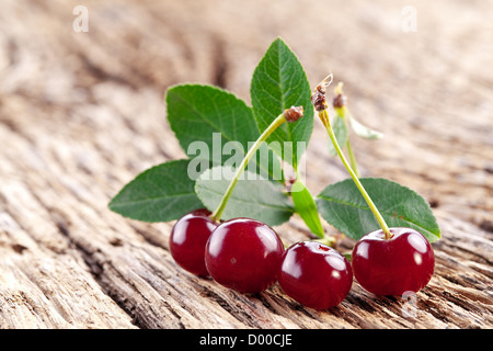 Le ciliegie con foglie su un vecchio tavolo di legno. Foto Stock