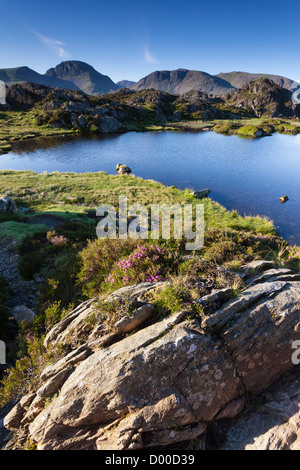 Il sorgere del sole su Innominate Tarn con Kirk cadde & grande timpano in distanza. Lake District, Inghilterra, Regno Unito. Foto Stock