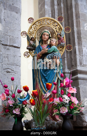 Vergine Maria tenendo in braccio Gesù Bambino statua e fiori Foto Stock