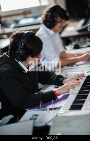 Due ragazzi adolescenti suonando piano tastiere in una sesta forma di musica lezione di classe ad un secondario completo scuola, Wales UK Foto Stock