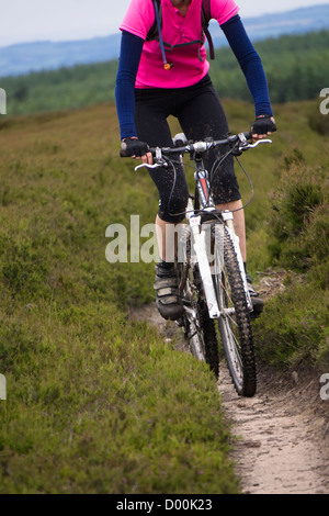 Una donna in sella la sua mountain bike attraverso le brughiere di erica vicino Blanchland in Northumberland. Foto Stock