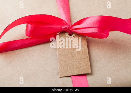 Close-up di un semplice pacchetto regalo con un nastro rosso e semplice carta. Foto Stock