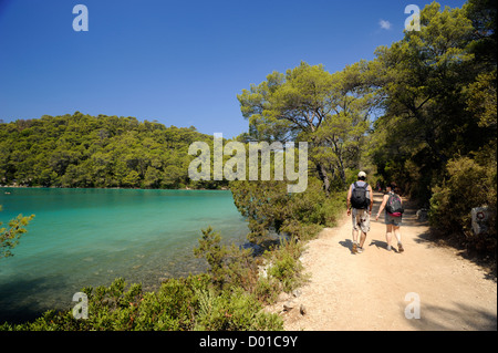 Croazia, Dalmazia, isola di Mljet, lago Malo Jezero, gente che cammina lungo il sentiero costiero Foto Stock