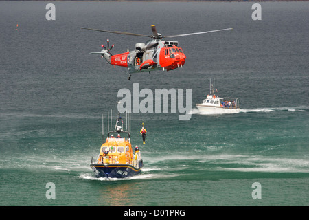 Un uomo di vino che viene abbassato su una barca di salvataggio da un elicottero di Ricerca e salvataggio al largo di Newquay, Cornovaglia, S W Inghilterra, durante un'esercitazione di salvataggio in mare. Foto Stock