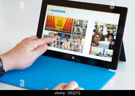 L'uomo la lettura di Al Jazeera news sito web app su Microsoft Surface rt computer tablet Foto Stock