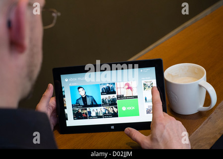 Uomo che utilizza Microsoft Surface rt computer tablet per navigare in music store Foto Stock