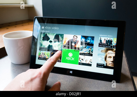 Uomo che utilizza Microsoft Surface rt computer tablet per sfogliare i filmati in video Microsoft store online Foto Stock
