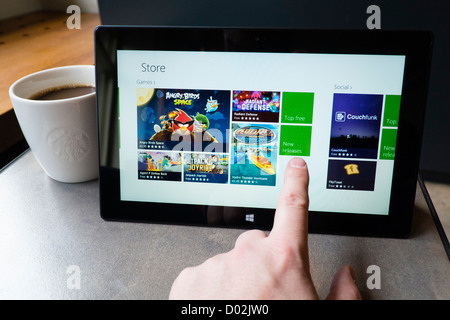 Uomo che utilizza Microsoft Surface rt computer tablet in cafe con la schermata che mostra App store Foto Stock