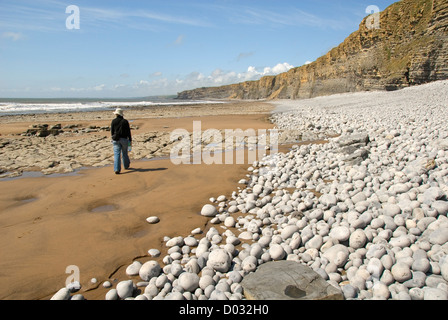 La donna a piedi lungo la spiaggia vicino a ripide scogliere, vicino al punto di Nash, Glamorgan Heritage Coast, Wales, Regno Unito Foto Stock