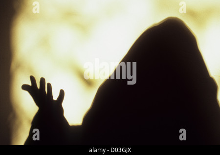 Ombra di frate incappucciato o sacerdote tenendo la sua mano in benvenuto o per sottolineare il suo intervento prima di brillante luce della finestra Foto Stock