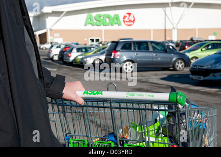 Primo piano di un uomo che spinge il carrello dello shopping del supermercato ASDA nel parcheggio fuori dal superstore Inghilterra Regno Unito Regno Unito Gran Bretagna Foto Stock