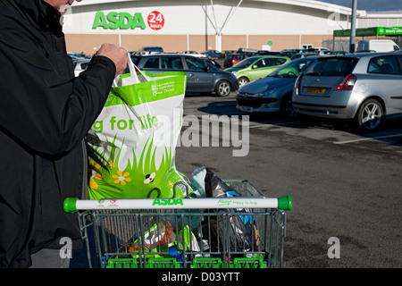 Primo piano di uomo con trasporto ASDA supermercato shopping Borse in carrello Inghilterra UK Regno Unito GB Gran Bretagna Foto Stock