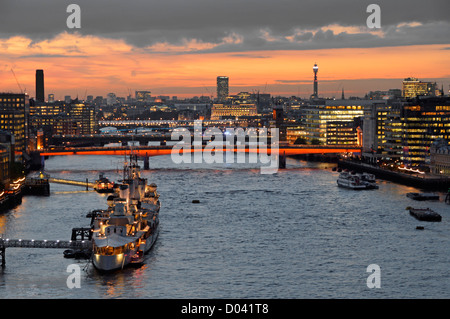 Vista aerea guardando in giù sul Fiume Tamigi e tramonto cityscape skyline di Londra HMS Belfast campi illuminati da London Bridge & office luci su edifici per uffici REGNO UNITO Foto Stock